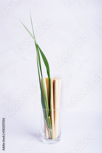 bamboo tubes, drinking straws in a transparent glass on a light background, eco friendly