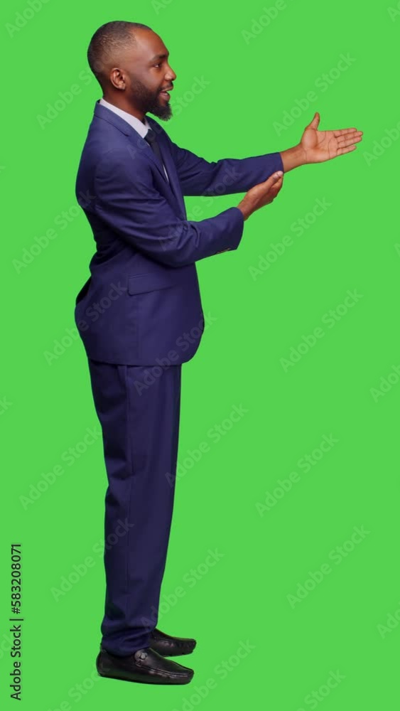 Vertical video: Profile of male entrepreneur creating advertisement on camera, talking about something on left or right sides. Professional company manager doing ad presentation over full body green Vertical video: Profile of male entrepreneur creating advertisement on camera, talking about something on left or right sides. Professional company manager doing ad presentation over full body green