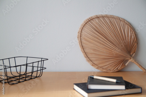 Stylish modern interior with wicker range on the wooden table, books, black box, decotarion, elegant personal accessories, modern home decor photo