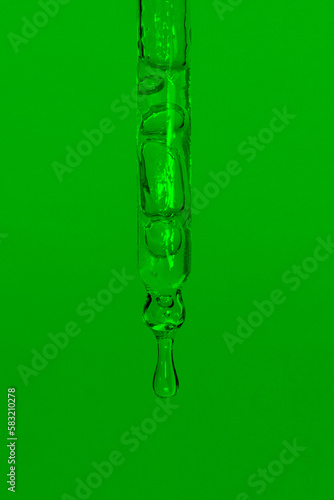 Cosmetic pipette with dripping liquid, oil and drops on a green background, serum, serum, gel, vitamin, water, oil. Natural cosmetic © Marina Red