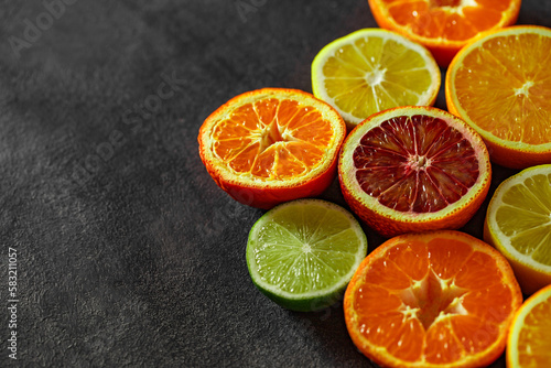 Citrus fruits cut in half, oranges, tangerines, lemons, limes, on dark background, top view, space to copy text © elenvd