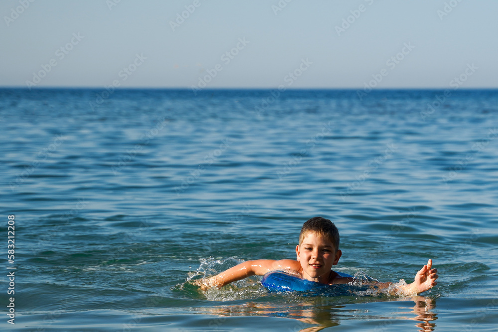 Boy happy swimming in the sea. The concept of a healthy lifestyle, doing sports.