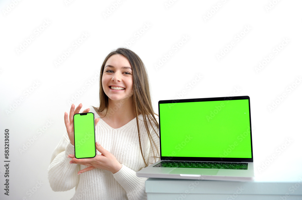 beautiful young girl in a white sweater shows a laptop with a chromakey She smiles advertises a product good presentation joy success win sale nice positive emotions on a white background Woman beautiful young girl in a white sweater shows a laptop with a chromakey She smiles advertises a product good presentation joy success win sale nice positive emotions on a white background Woman