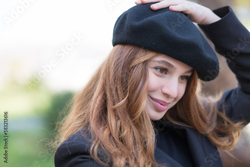 a stunning look of a beautiful young girl with long curly red hair wearing a beret and black top photo