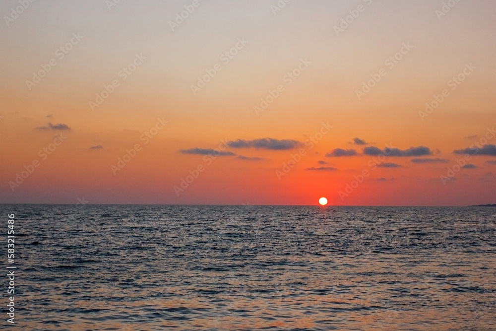 Sunset over the sea, red sun at the surface of the water Sunset over the sea, red sun at the surface of the water
