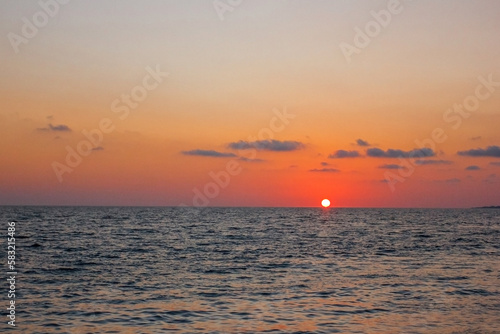 Sunset over the sea, red sun at the surface of the water