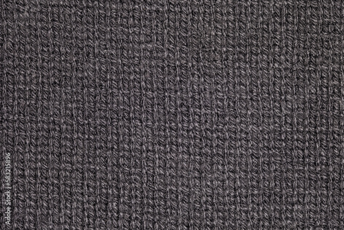 Fabric knitted with black spinning threads close-up knitting, background wallpaper, uniform texture pattern