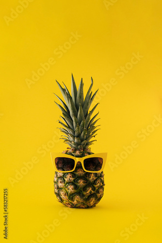 Fresh pineapple with sunglasses on yellow background. Minimal summer furit concept.
