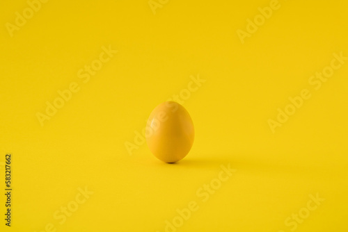 Yellow colored egg on yellow background. Minimal Easter concept.
