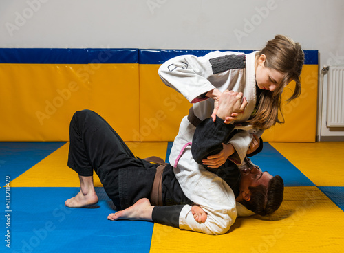 Young girl and boy practice Brazilian jiu jitsu in the gym