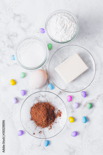 Wallpaper Mural Ingredients for cooking. Eggs, cacao, piece of butter, flour, sugar, colorful candy eggs on table. Ingredients for making dough. Ingredients for baking cookies. Top view. Torontodigital.ca
