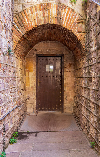 Antique wooden door in oval stone structure of orange tone