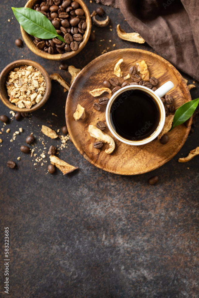 Mushroom coffee in a cup and coffee beans, trendy drink on a stone background. Healthy organic energizing adaptogen. View from above. Copy space. Mushroom coffee in a cup and coffee beans, trendy drink on a stone background. Healthy organic energizing adaptogen. View from above. Copy space.