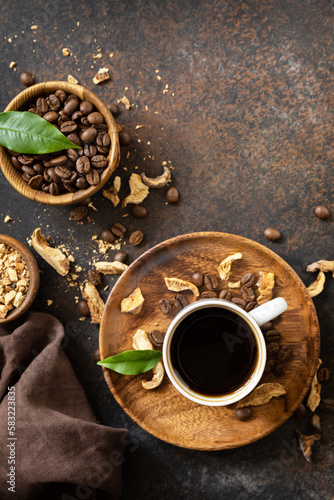Mushroom coffee in a cup and coffee beans, trendy drink on a stone background. Healthy organic energizing adaptogen. View from above.