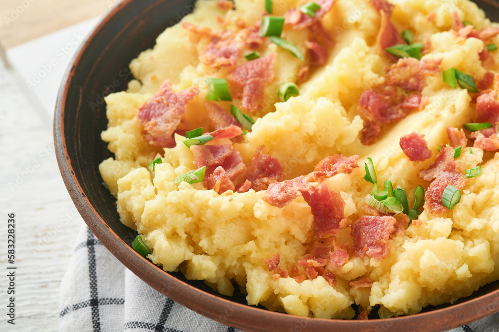 Mashed boiled potatoes. Bacon mashed potatoes with green onion, pepper and cheddar cheese in bowl on light old wooden backgrounds. Delicious creamy mashed potatoes. Top view. Mashed boiled potatoes. Bacon mashed potatoes with green onion, pepper and cheddar cheese in bowl on light old wooden backgrounds. Delicious creamy mashed potatoes. Top view.