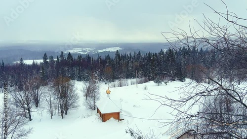 View of the chapel near the Belogorsky St. Nicholas Orthodox Missionary Monastery. Winter forest. The temple on the hill in winter. Russia, Perm Krai, Belaya Gora. 4K photo