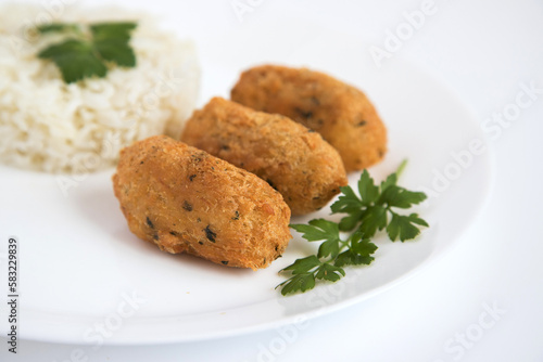 Cod dumplings, or "bolinhos de bacalhau", very famous in Portuguese gastronomy. Fried dumpling, cod dumpling, fish, salted cod fritters, bacalao bunuelos. Plate of cod pastries served with white rice.