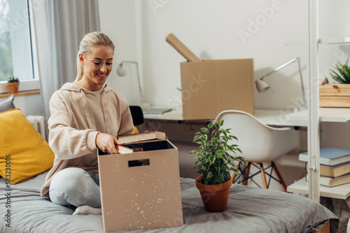 female student moving in dorm room, she is unpacking her staff photo