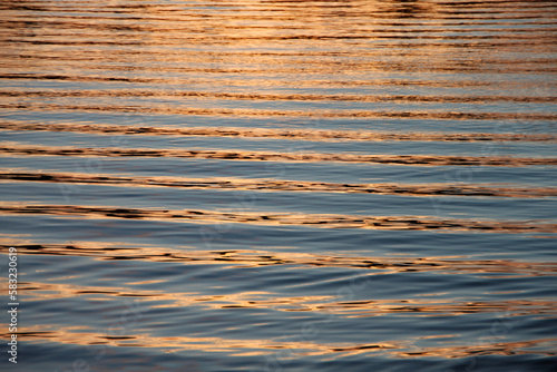 beautiful landscape of perfect ripples of sea water with orange color reflecting the sunset light