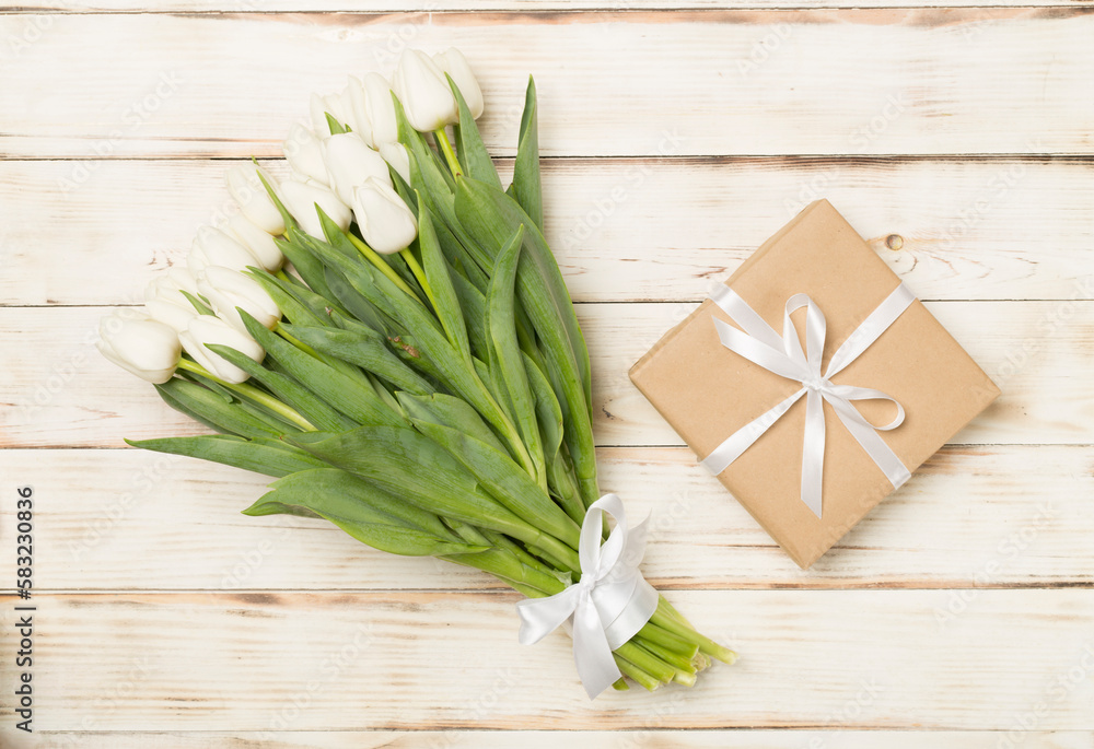 White tulip bouquet with gift box on wooden background, top view White tulip bouquet with gift box on wooden background, top view