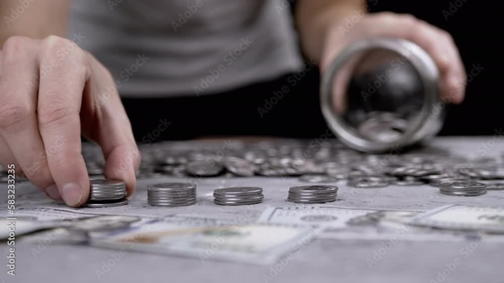 Woman Putting a Stack of Silver Coins into a Glass Jar or Piggy Bank. A lot of cents, cash is lying on a concrete background. Budget, spending, savings, accumulation. Wealth, poverty. Finance. Stock. Woman Putting a Stack of Silver Coins into a Glass Jar or Piggy Bank. A lot of cents, cash is lying on a concrete background. Budget, spending, savings, accumulation. Wealth, poverty. Finance. Stock.
