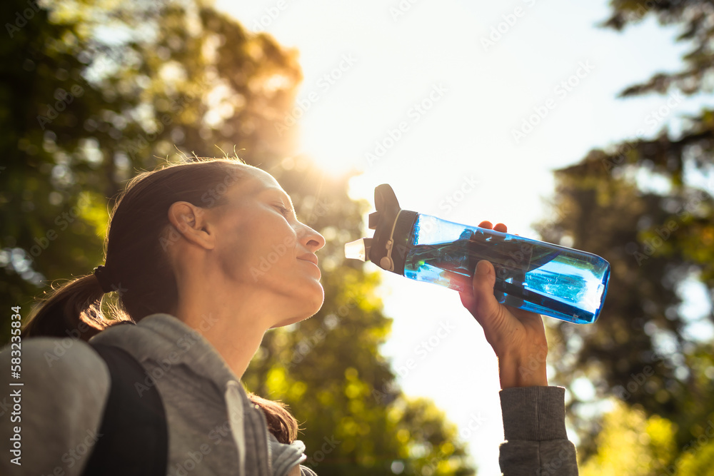 Young female enjoying a refreshing drink of water  - obrazy, fototapety, plakaty 