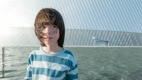 Portrait of boy on building background in windy conditions