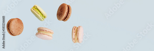 Lots of macarons falling down isolated on blue background. Background for the confectionery menu. Banner for website header design with copy space.