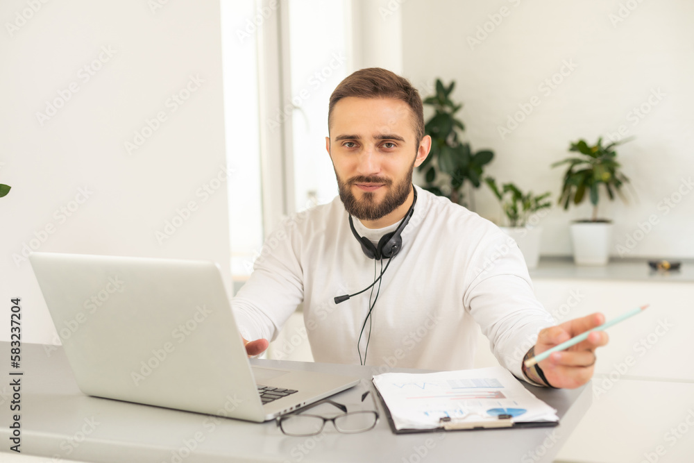 Multi-tasking businessman working in the office. He is using touchpad while reading an e-mail on laptop and taking notes on the paper Multi-tasking businessman working in the office. He is using touchpad while reading an e-mail on laptop and taking notes on the paper