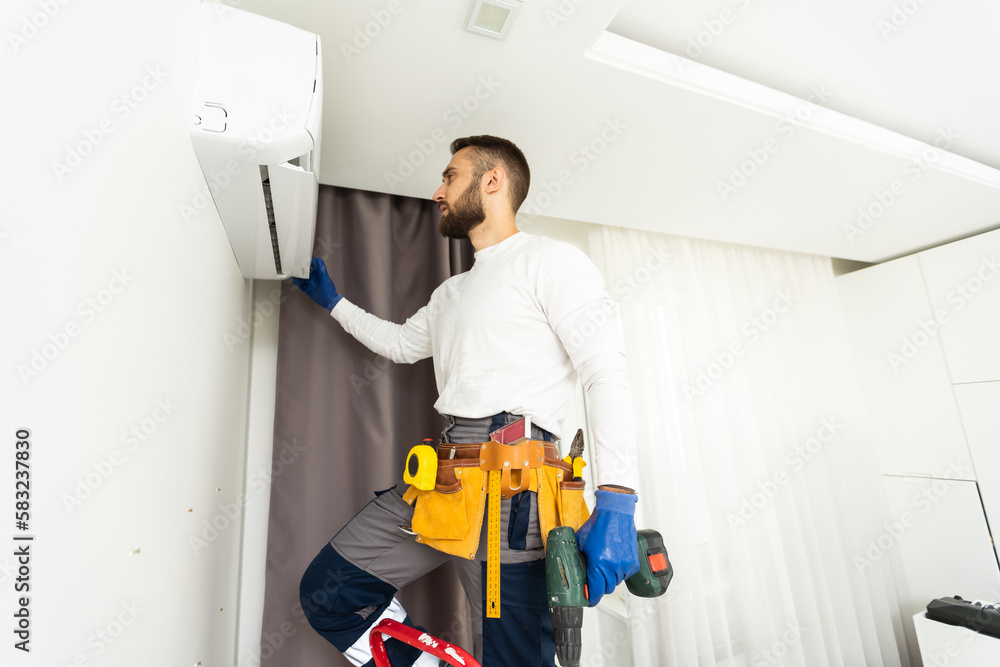 Male technician fixing air conditioner indoors. Male technician fixing air conditioner indoors.