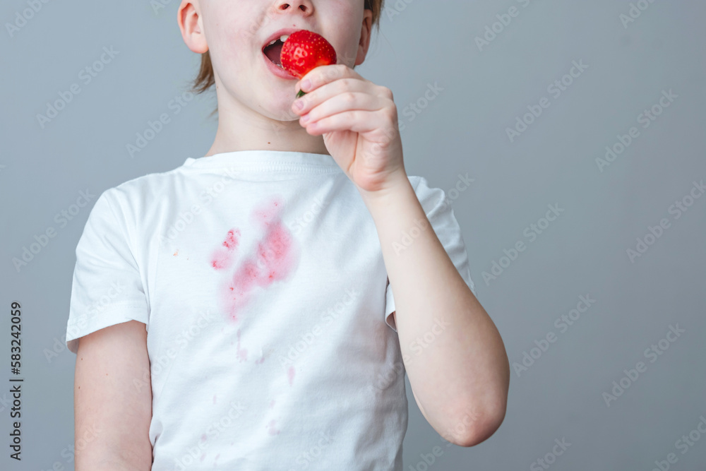 Splashes of strawberry juice ruined the perfect outfit. A boy eating
