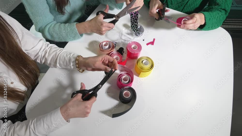 Lifting skin concept. Kinesiotaping. Girls sit at table and cut multi-colored kinesiotage tape with scissors. Many women are trained in applications from tapes. On table tape. Skin and body care. Lifting skin concept. Kinesiotaping. Girls sit at table and cut multi-colored kinesiotage tape with scissors. Many women are trained in applications from tapes. On table tape. Skin and body care.