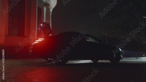Night outdoors scene, trunk of a car opens automatically, woman comes and takes a sparkling dress, red car lights. Preparing for black tie event, concert or night show occasion. Slo mo HQ 4k footage