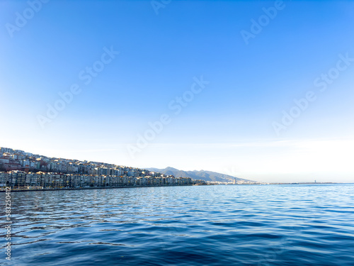 scenic view of the mediterranean sea from İzmir, Türkiye, Konak. Seascape with city and mountain silhouette at left corner, blue sea and sky background