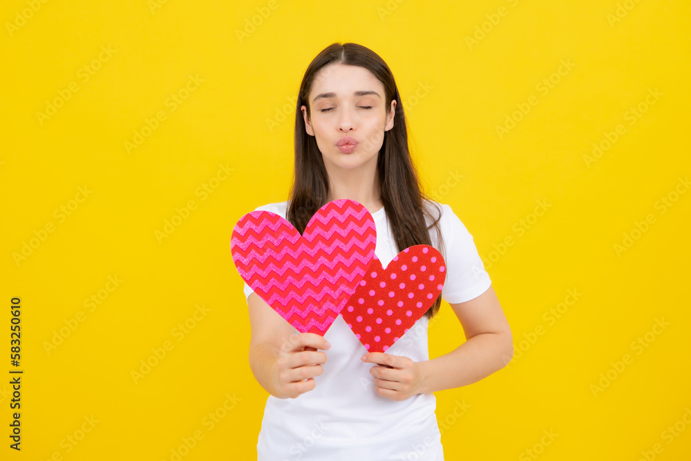 Portrait of pretty smiling woman holding paper heart in her hands on yellow background. Love concept. Love sign symbols for happy womens, valentines day or birthday. Portrait of pretty smiling woman holding paper heart in her hands on yellow background. Love concept. Love sign symbols for happy womens, valentines day or birthday.