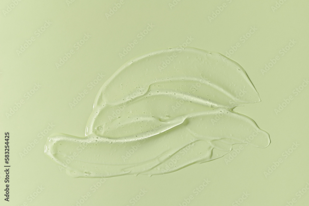 Fototapeta premium Cosmetic transparent gel serum swatch with bubbles isolated on green background.