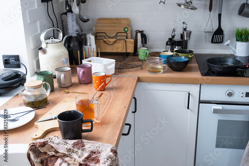 A mess in the kitchen, dirty dishes on the table, scattered things, unsanitary conditions. The dishwasher is full, the kitchen is untidy, everyday life photo
