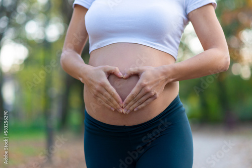 Making Heart Shape by her Hands on Belly. Body Part. Enjoying Pregnancy. Young Happy Family