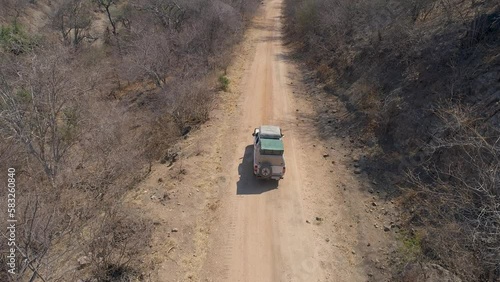 Aerial drone footage of three white expedition safari cars driving in the dry African landscape. Self drive safari, Wildlife expedition, Zimbabwe, en route to ManaPools. photo