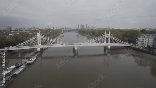  bridge spanning Thames river. Trees in park on waterfront and downtown buildings in distance. London, UK