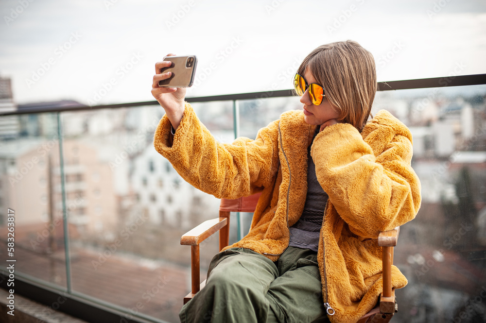 Foto de Beautiful young girl in a yellow fur coat is sitting in a ...