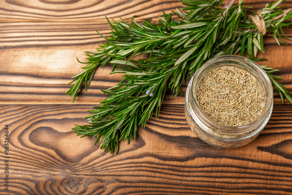 Dried rosemary in a glass jar, branches of fresh rosemary on a brown wooden background.Spices and herbs for meat and fish.Recipe.Culinary concept.Organic herbs. Place for text. Dried rosemary in a glass jar, branches of fresh rosemary on a brown wooden background.Spices and herbs for meat and fish.Recipe.Culinary concept.Organic herbs. Place for text.