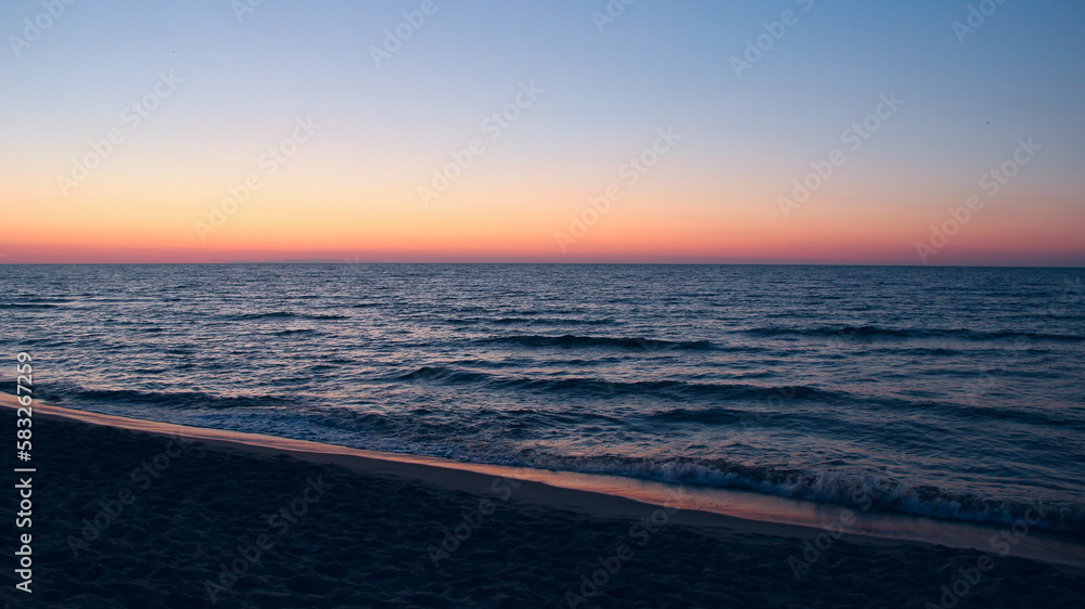 Sunset on Baltic Sea. Waves on seashore in evening