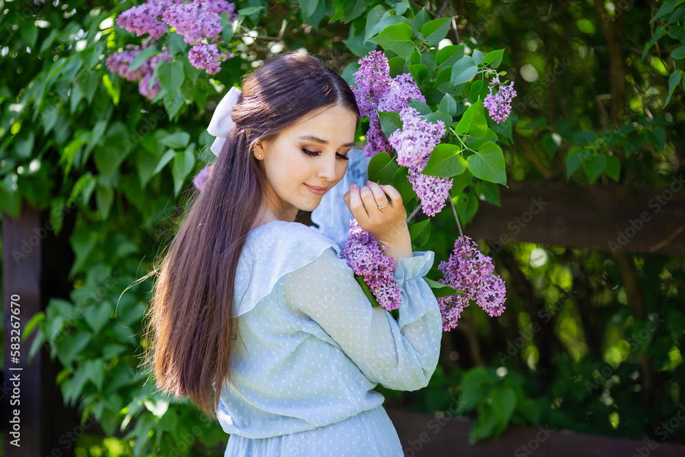 romantic girl in blue dress stands with lilac flowers, in the garden romantic girl in blue dress stands with lilac flowers, in the garden