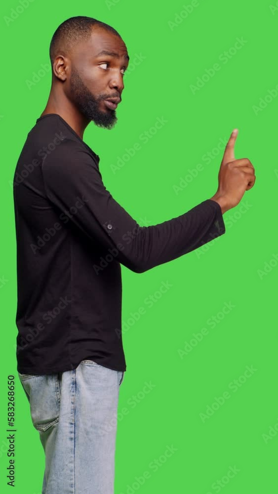 Vertical video: Profile of african american man showing no symbol with finger, doing rejection and denial gesture in studio. Young male model expressing disapproval and refusal sign over greenscreen Vertical video: Profile of african american man showing no symbol with finger, doing rejection and denial gesture in studio. Young male model expressing disapproval and refusal sign over greenscreen