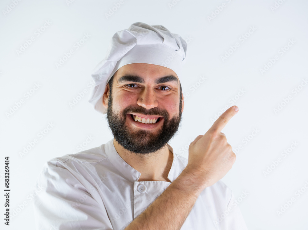 Young male chef pointing right while smiling and looking at camera. Isolated on a white background Young male chef pointing right while smiling and looking at camera. Isolated on a white background