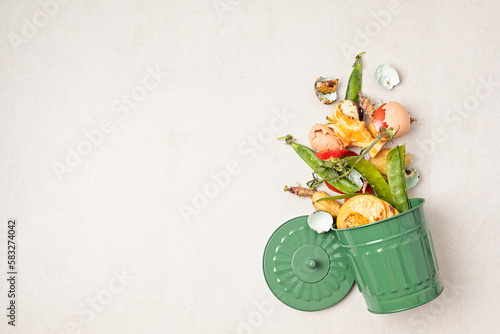 Green compost bin and kitchen leftovers. Recycling scarps, sustainable and zero waste lifestyle concept. Fruits and vegetable garbage waste turning into organic fertilizerd soil. Top view, flatlay photo