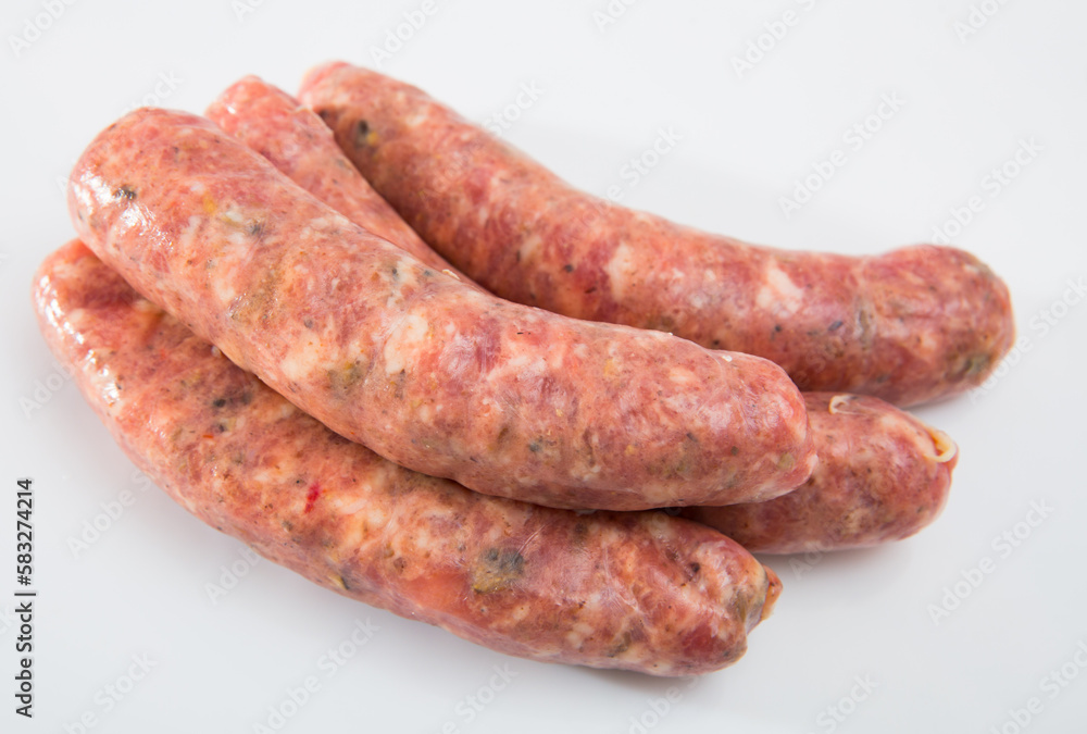 Uncooked homemade sausages with mushrooms on white surface
