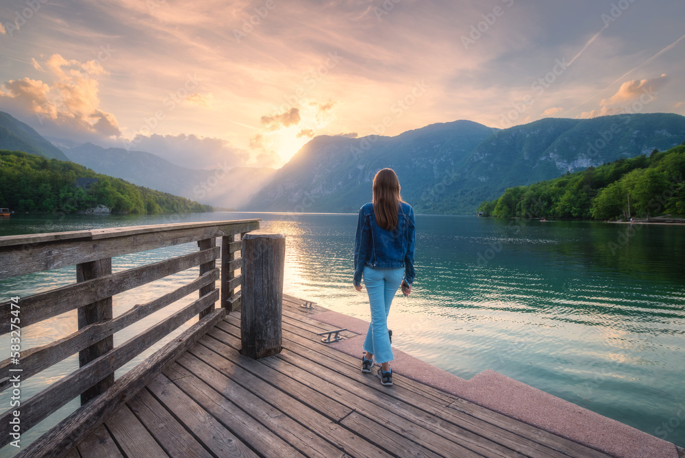 Woman and mountains reflected in lake at sunset in autumn Woman and mountains reflected in lake at sunset in autumn