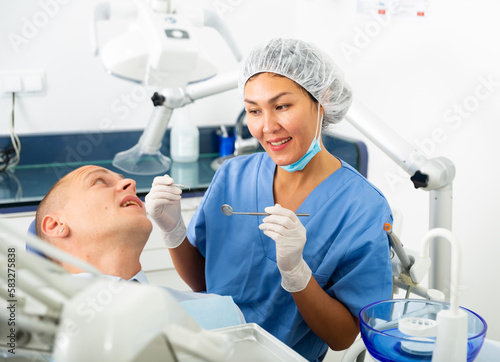 Positive female dentist preparing for a male oral examination